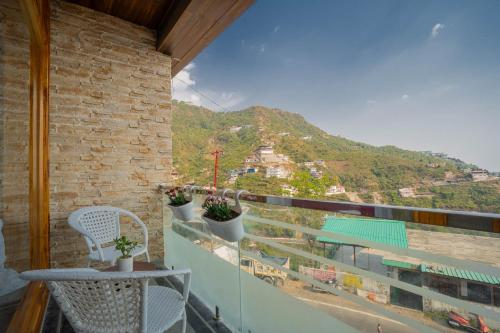 a balcony with a table and chairs and a mountain at PerfectStayz Value Paradise near Bhatta Falls in Mussoorie