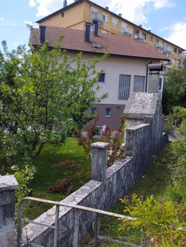 a stone retaining wall in front of a house at Apartman Šljivo in Konjic