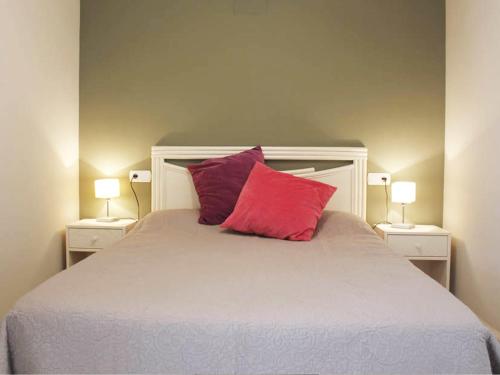 a bed with two red pillows and two lamps at Apartamentos Topacio Unitursa in Calpe