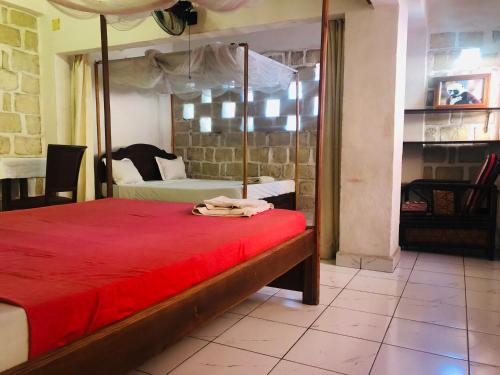 a bedroom with a bed with a red comforter at Chez Tranquilllle hôtel in Mahajanga