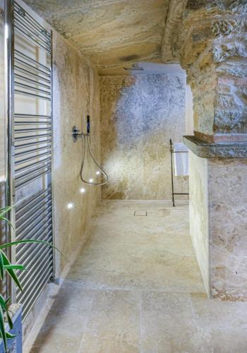 a bathroom with a shower in a stone wall at Il Falconiere Relais & Spa in Cortona