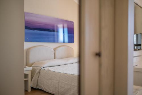 a bedroom with a bed with a painting on the wall at Hotel Punta Negra in Alghero