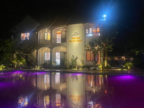 un edificio con luces púrpuras en el agua por la noche en Tam Coc Galaxy Villa en Ninh Binh