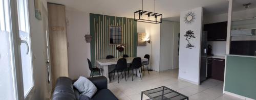 a living room with a couch and a table with chairs at Maison de ville proche Le Portel 2 chambres in Outreau