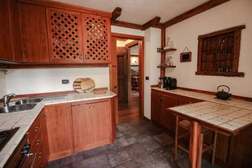 a kitchen with wooden cabinets and a sink and a table at Monte Bianco elegant villa apartment Courmayeur in Pré-Saint-Didier