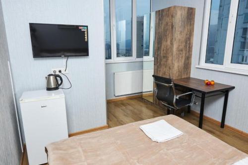 um quarto com uma secretária, uma televisão e uma mesa em Goodwill XXL10 em Tbilisi