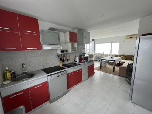 cocina con armarios rojos y blancos y sala de estar. en Apartament Costinești vedere epavă, en Costinesti