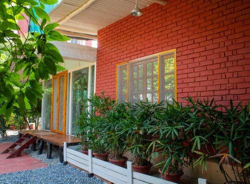 un banc assis à l'extérieur d'un bâtiment rouge avec des plantes dans l'établissement ITH Luxury Family Cottage – Hibiscus, à Varanasi