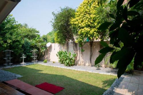 un jardín con una pared y un patio con una alfombra roja en ITH Luxury Cottage 'Hibiscus' en Varanasi