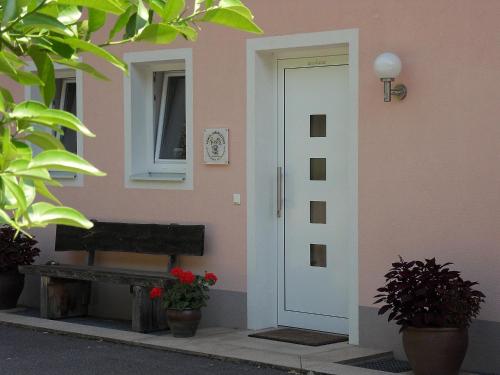 a door to a house with a bench and flowers at FeWo in der Weinleiten in Millstatt