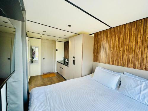 a bedroom with a white bed and a wooden wall at The Jade Highlands Mountain View Cozy container 2bhk villa in Kodaikānāl