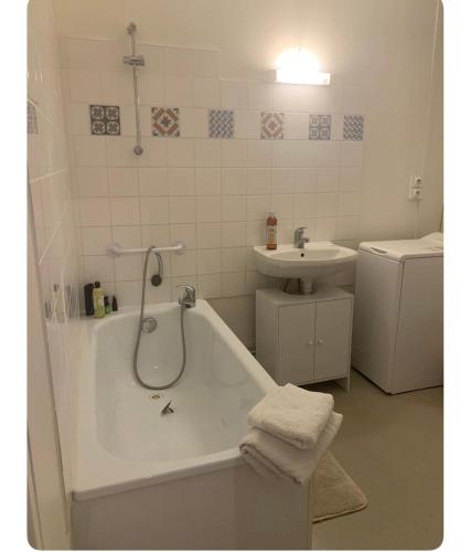 une salle de bain blanche avec une baignoire et un lavabo dans l'établissement Appartement spacieux et lumineux, à Vandœuvre-lès-Nancy