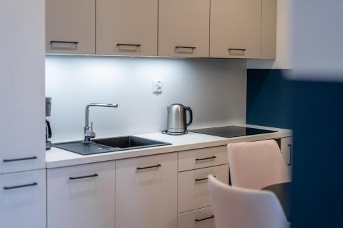 a kitchen with a sink and white cabinets at FARO Apartamenty Polanki Aqua SPA Deluxe 4 baseny w cenie, Pools inklusive in Kołobrzeg