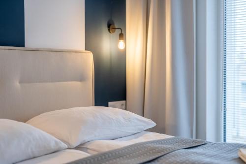 a bed with a white pillow and a window at FARO Apartamenty Polanki Aqua SPA Deluxe 4 baseny w cenie, Pools inklusive in Kołobrzeg