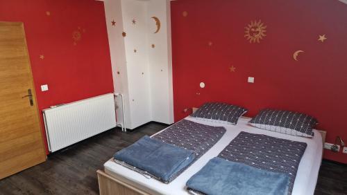 1 dormitorio con 2 camas y pared roja en Hiša Bizjak, en Kranj