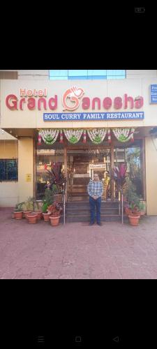 a man is standing in front of a store at Hotel Grand Ganesha in Ganpatipule