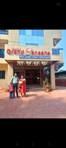 a man and two children standing in front of a building at Hotel Grand Ganesha in Ganpatipule
