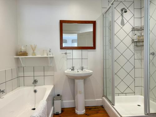 a bathroom with a tub and a sink and a mirror at Valley View Cottages in Cape Town