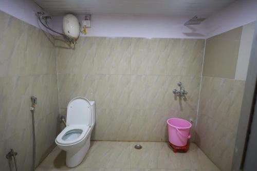 a bathroom with a toilet and a pink bucket at Raj Resort in Patna