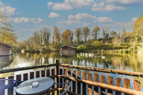 a table and chairs sitting on a deck next to a river at Herons Lake Retreat Lodges in Caerwys