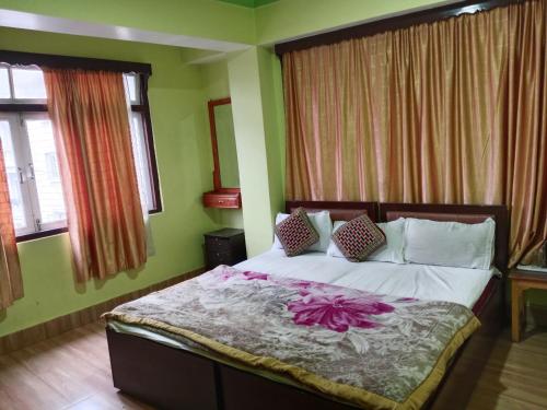 a bedroom with a bed with pink flowers on it at Zimkhang Guesthouse in Gangtok