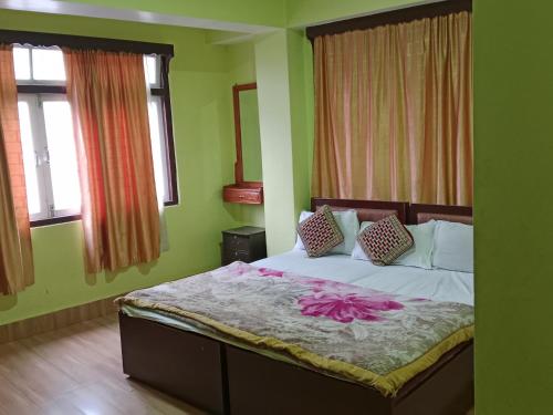 a bed in a room with green walls and windows at Zimkhang Guesthouse in Gangtok