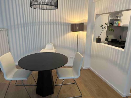 Appartement DUS في دوسلدورف: طاولة سوداء مع كراسي بيضاء وطاولة سوداء