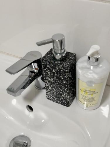 un lavandino in bagno con una bottiglia di sapone e un dispenser di sapone di The Legacy a East London