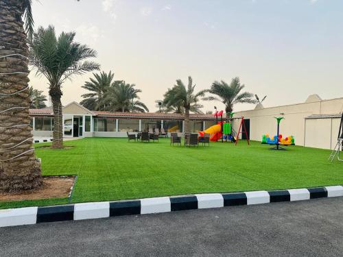 a yard with a playground with palm trees and a house at استراحة تل الشمال5 in Riyadh