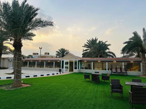a house with a green yard with chairs and a palm tree at استراحة تل الشمال5 in Riyadh
