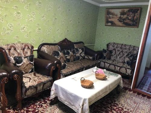 uma sala de estar com sofás, uma mesa e um espelho em Korzinka em Fergana