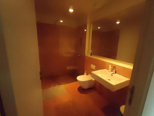 La salle de bains est pourvue d'un lavabo, de toilettes et d'un miroir. dans l'établissement Designer home with pool near beach and village, à Alella