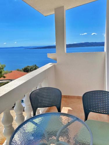 Un balcón con una mesa de cristal y sillas y el océano. en Villa Stipuka en Brela