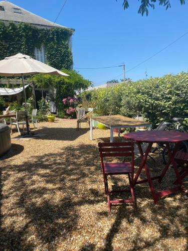 une table de pique-nique avec une chaise et un parasol dans l'établissement Chambres de la Choisille à Fondettes st Cyr Tours, à Fondettes