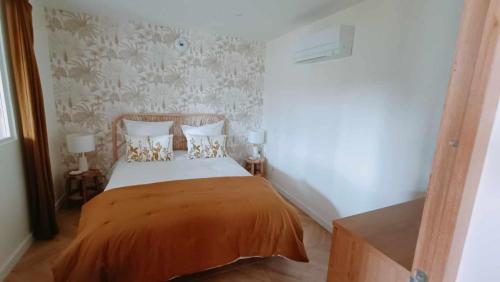 um quarto com uma cama com lençóis e almofadas laranja em Bas de Villa neuf en Provence avec Piscine em Mallemoisson