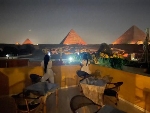 Duas mulheres sentadas num telhado a olhar para as pirâmides. em Pyramids Plateau View no Cairo