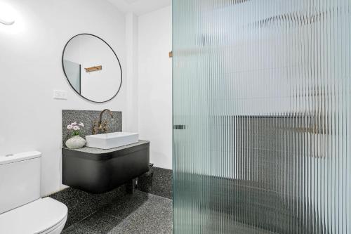 a bathroom with a glass shower with a toilet and a sink at The Electric Hotel in Geelong