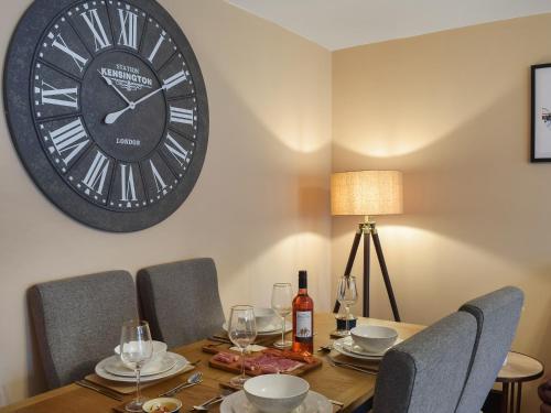 a dining room table with a large clock on the wall at Riverview in Bridge of Allan