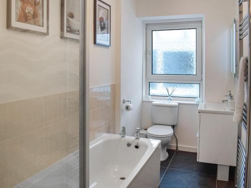 a bathroom with a tub and a toilet and a window at Riverview in Bridge of Allan