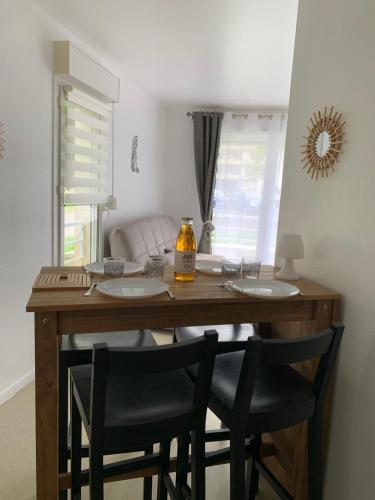 une table de salle à manger avec deux chaises et une bouteille de miel dans l'établissement La colline aux oiseaux, à Caen