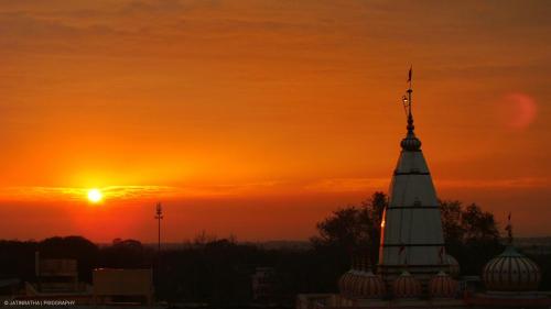 een uitzicht op de zonsondergang van een gebouw met een toren bij Anand Yatri Grah, Ujjain in Ujjain