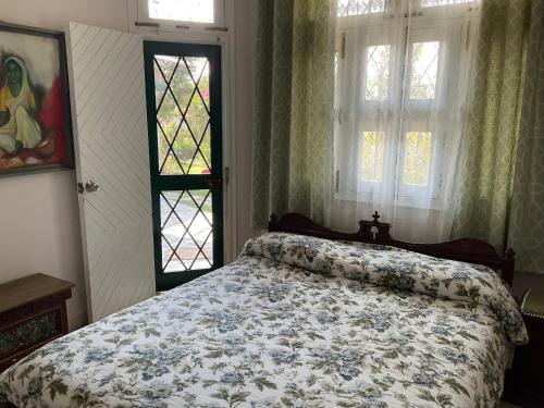 a bedroom with a bed with a floral bedspread and windows at Chinarchalet in Pālampur