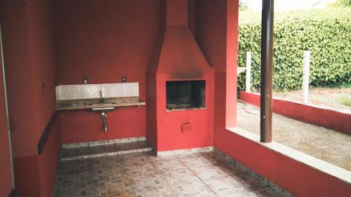 um quarto com uma parede vermelha e uma lareira em Rancho Ponta do Sol em Capitólio