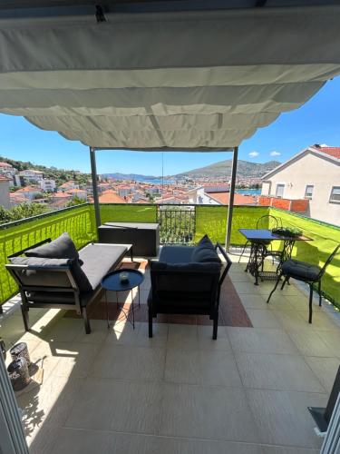 un patio con sillas, mesas y una sombrilla blanca en Apartment Salov, en Trogir
