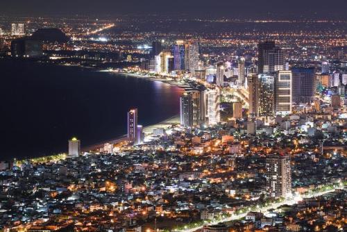 a city lit up at night with a river and buildings at Luxury Apartment - Rooftop Swimming Pool - Beach Front - Hinata Apartment in Da Nang