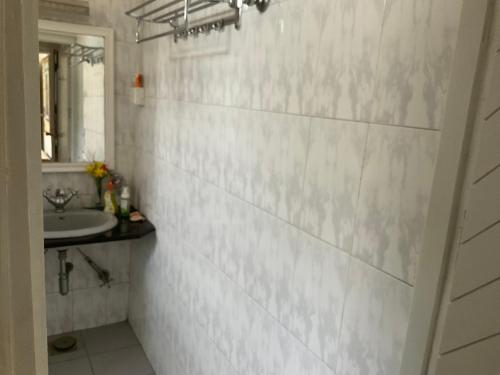 a bathroom with a sink and a white tile wall at Chinarchalet in Pālampur
