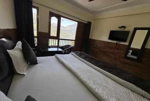 een slaapkamer met een groot bed en een televisie bij Goroomgo Rohila Lodge Nainital Near Naini Lake - Luxury Room Mountain View in Nainital