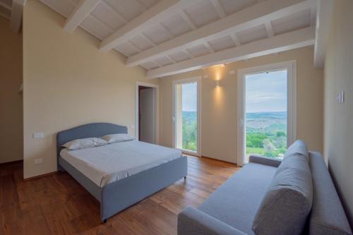 1 dormitorio con cama, sofá y ventana grande en AlMiFiole, en Montegridolfo