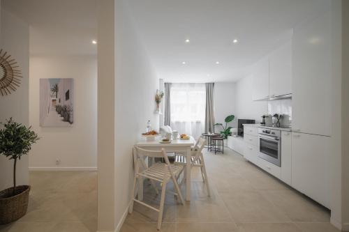 une cuisine avec des armoires blanches et une table et des chaises dans l'établissement Spacieux Summer Getaway Ideal Apartment for 6, à Nice