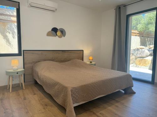 1 dormitorio con cama y ventana grande en Aria Linda, en Belgodère